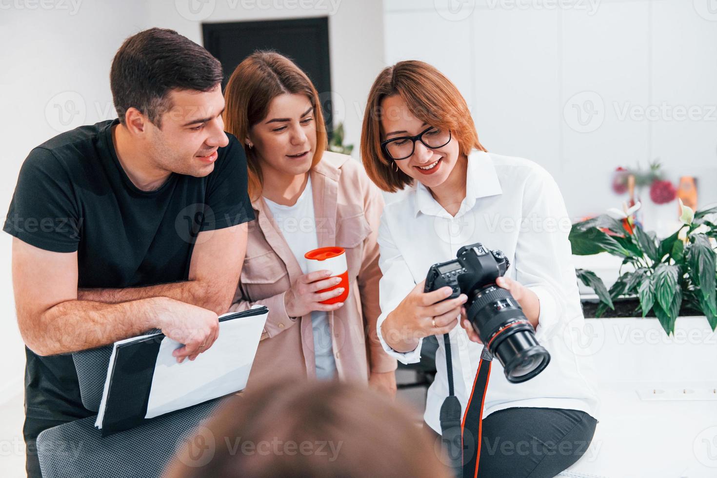 Group of business people in formal clothes indoors in the office looking at photos on the camera