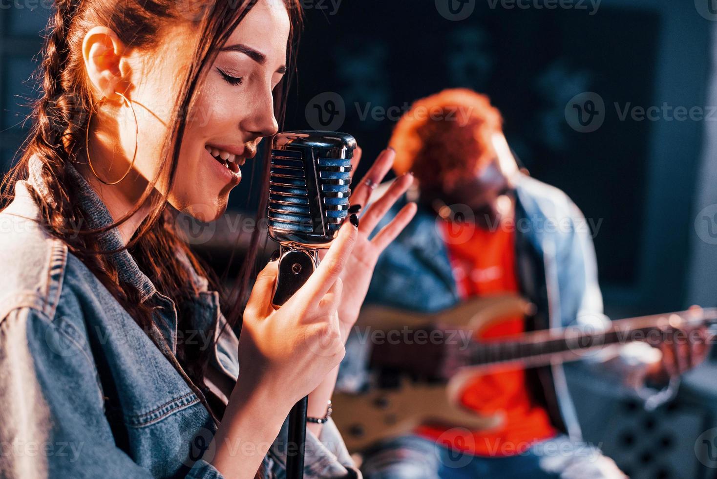 Guy plays guitar, girl sings. African american man with white girl rehearsing in the studio together photo