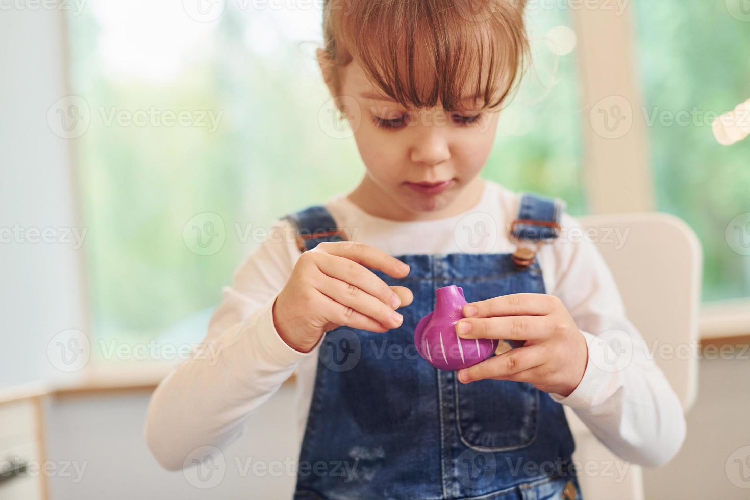 Little girl in casual clothes have fun by playing with toys on the kitchen photo