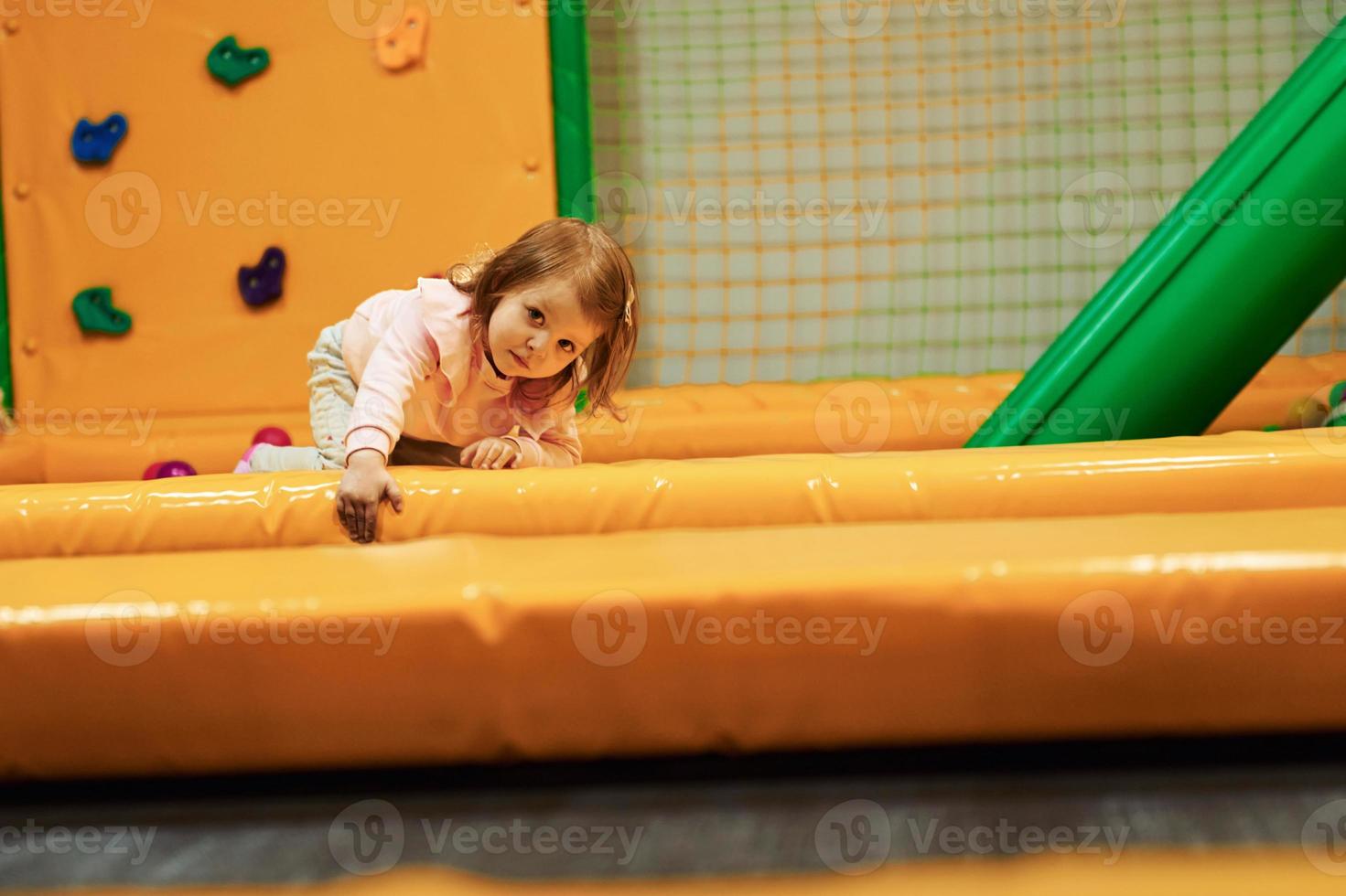 Happy little girl in casual clothes have fun in children's game complex photo