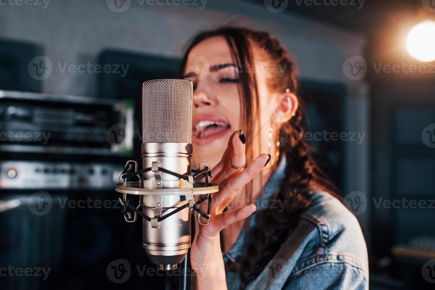 Young beautiful female performer rehearsing in a recording studio photo