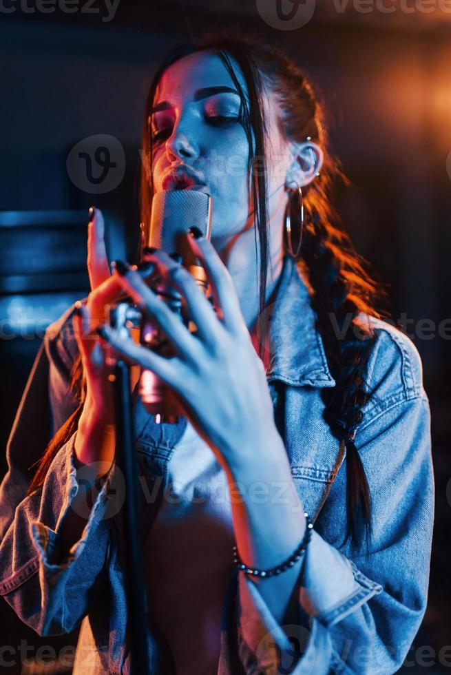 Young beautiful female singer rehearsing in a recording studio photo