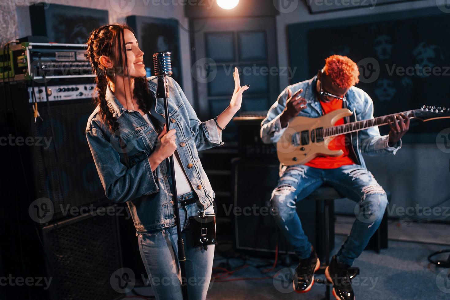 Guy plays guitar, girl sings. African american man with white girl rehearsing in the studio together photo