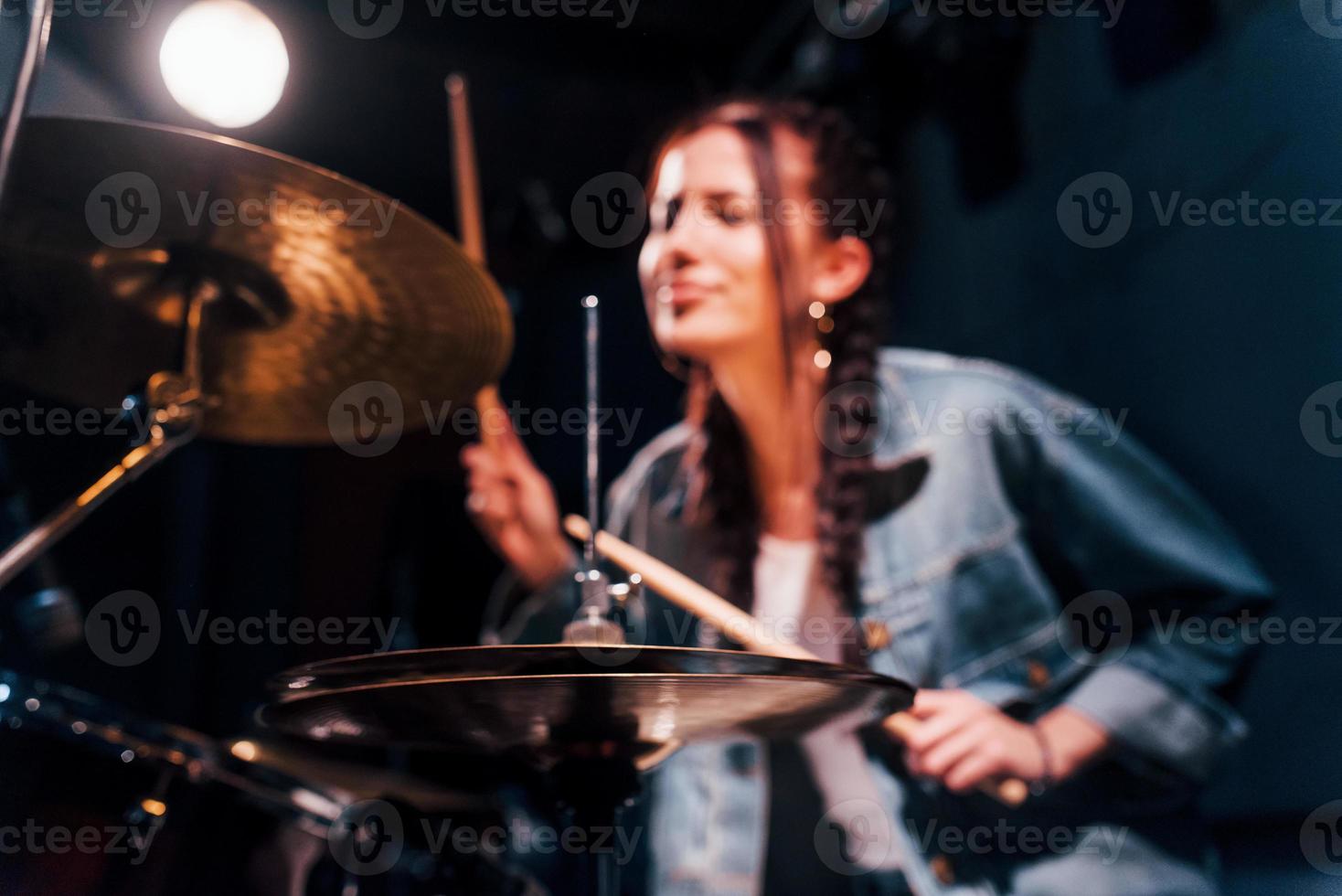 Plays drums. Young beautiful female performer rehearsing in a recording studio photo