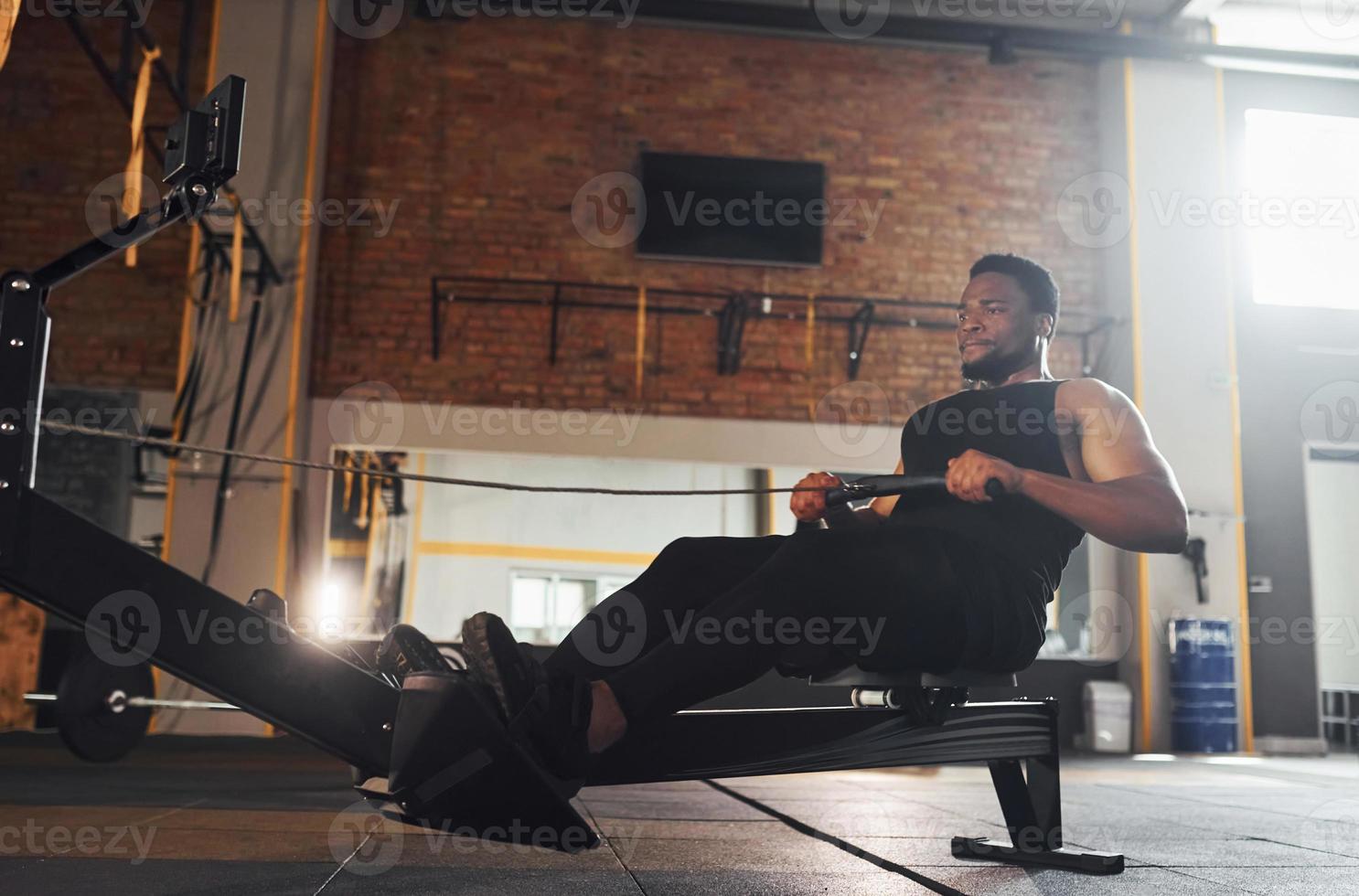 Strong african american man in sportive clothes have workout day in the gym by using equipment photo