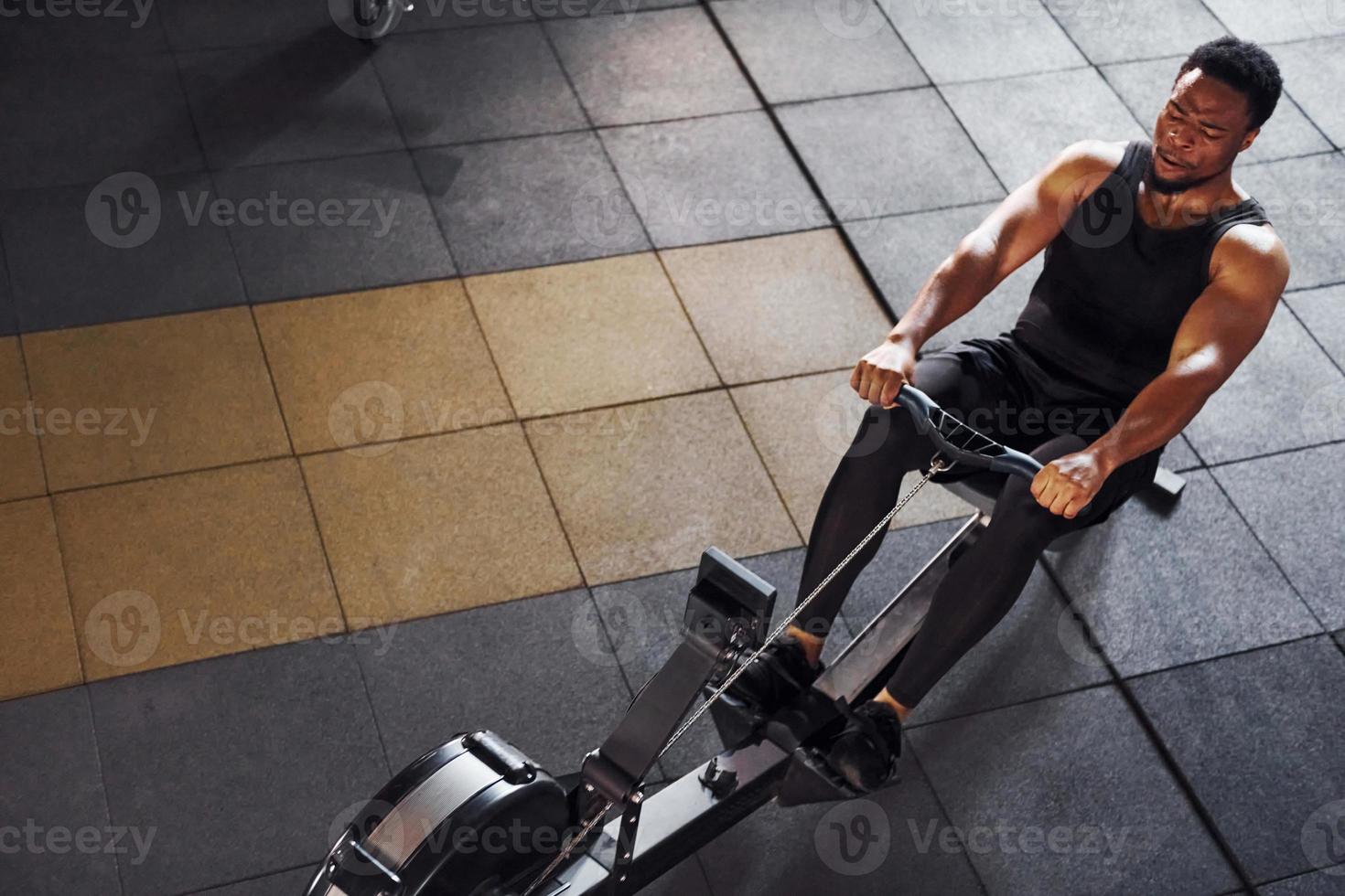 Strong african american man in sportive clothes have workout day in the gym and using equipment. Conception of power and strength photo