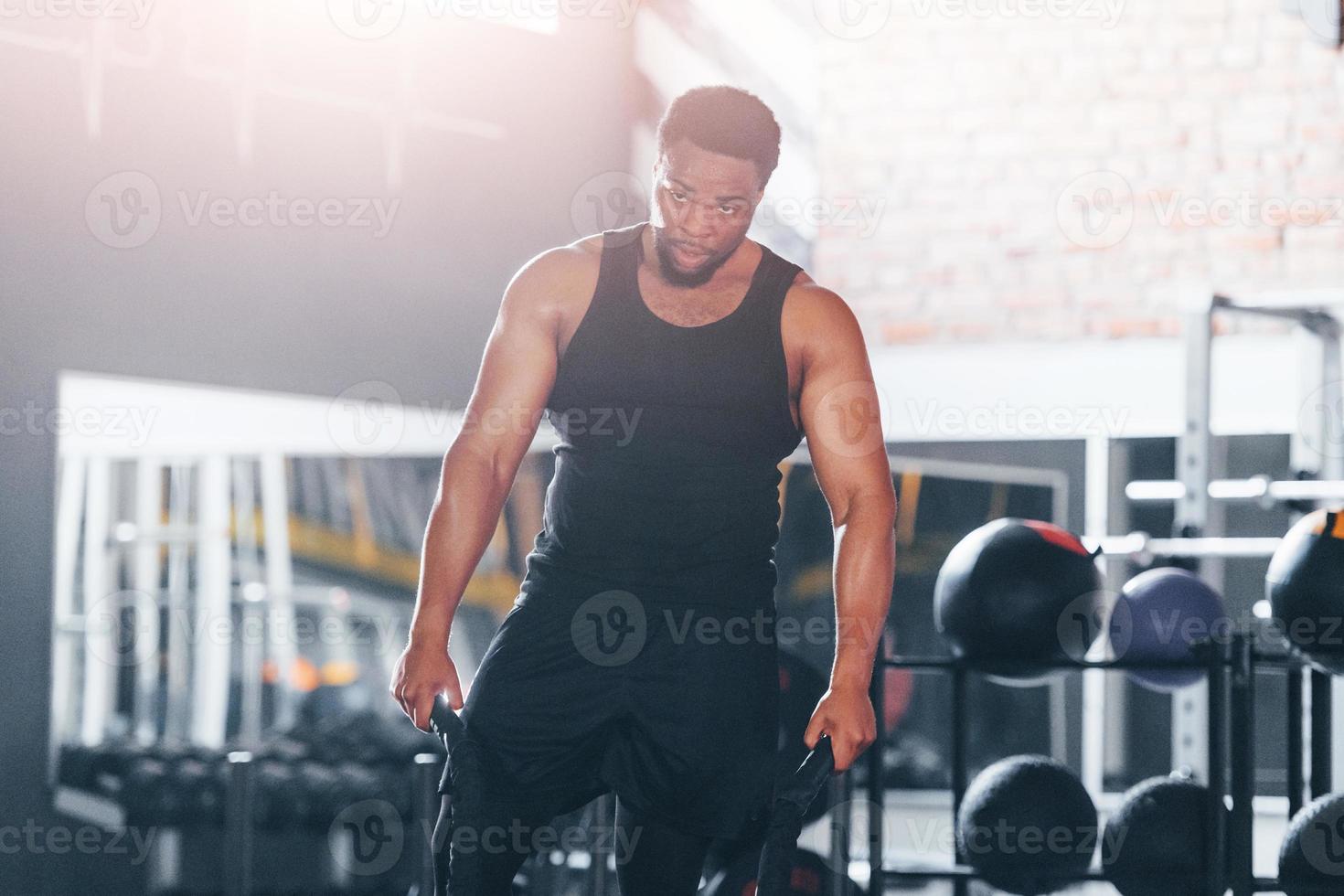 un hombre afroamericano fuerte con ropa deportiva tiene un día de  entrenamiento en el gimnasio. haciendo crossfit usando cuerdas 15293774  Foto de stock en Vecteezy