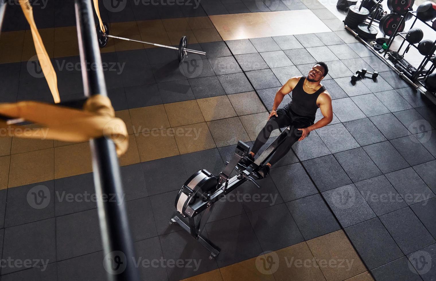 Strong african american man in sportive clothes have workout day in the gym and using equipment. Conception of power and strength photo