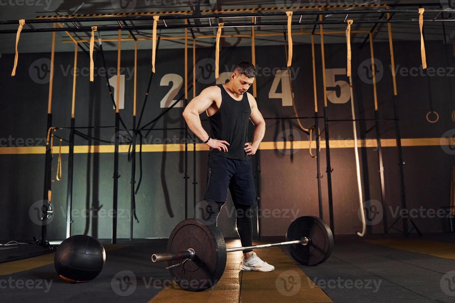 Strong man in sportive clothes lifting barbell in the gym photo