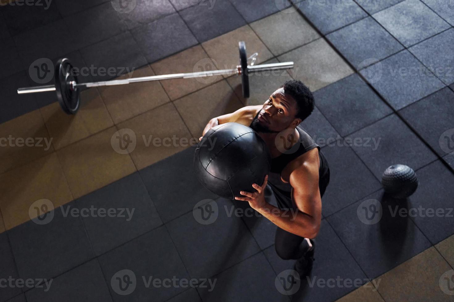 Playing basketball. Strong african american man in sportive clothes have workout day in the gym photo