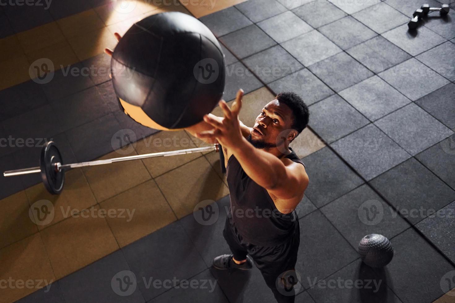 Playing basketball. Strong african american man in sportive clothes have workout day in the gym photo