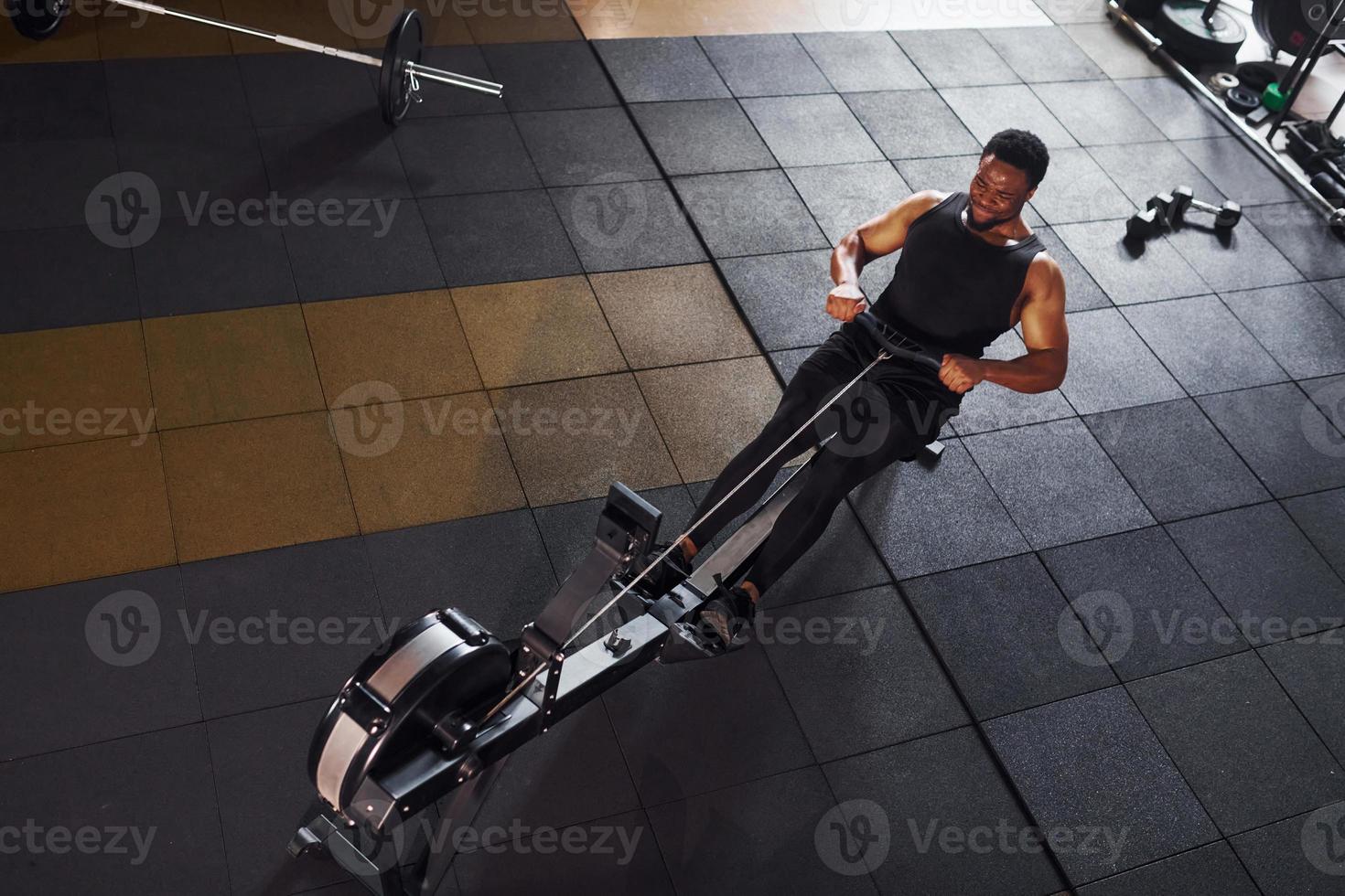 Strong african american man in sportive clothes have workout day in the gym and using equipment. Conception of power and strength photo