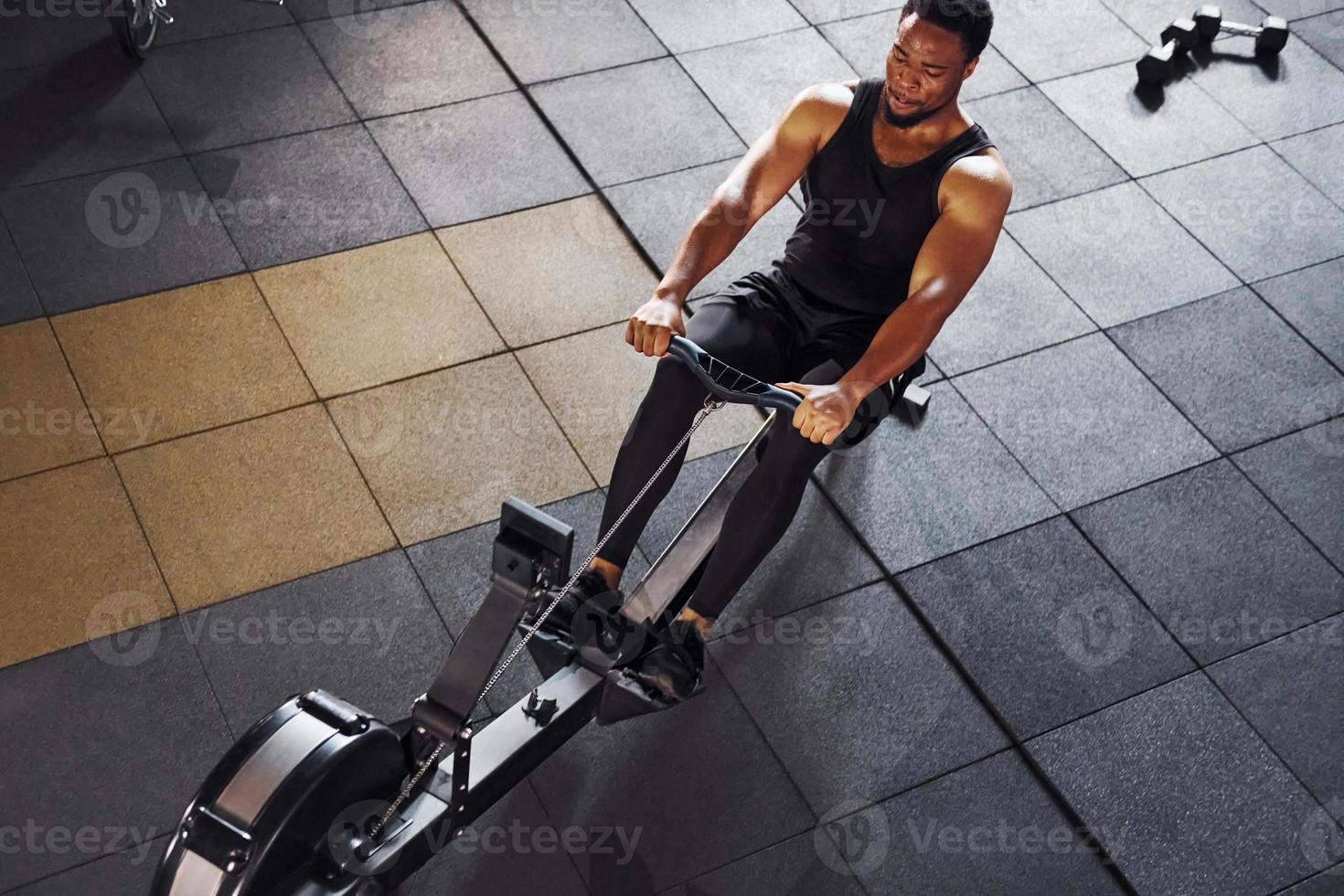 Strong african american man in sportive clothes have workout day in the gym and using equipment. Conception of power and strength photo