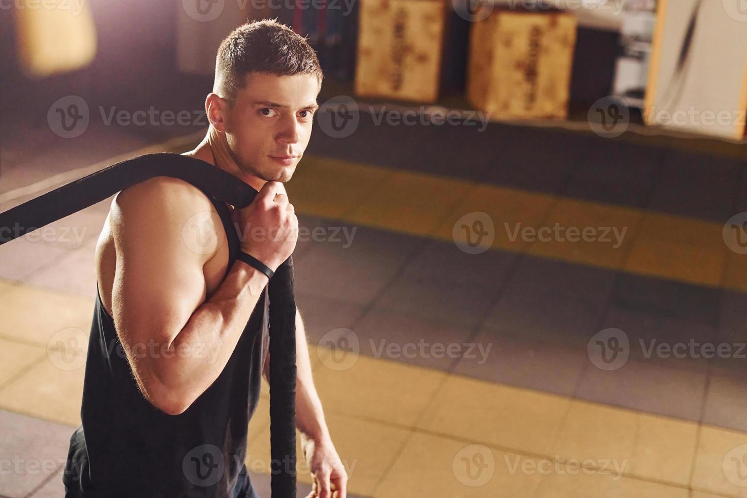 Strong man in sportive clothes have workout day in the gym by using rope photo