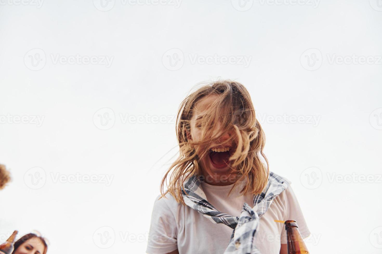 una joven sonriente positiva se divierte y sus amigos y mira a la cámara foto