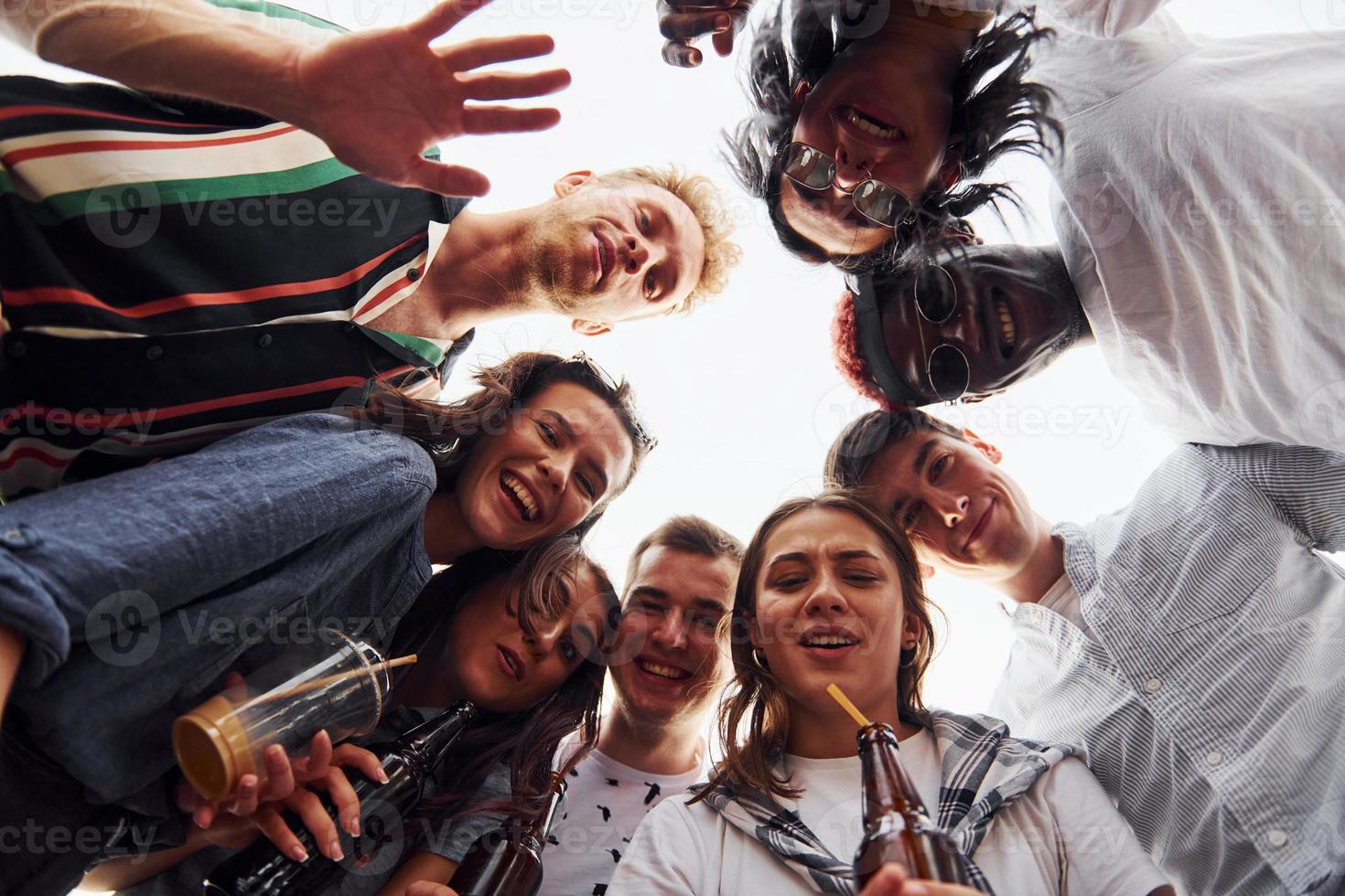 Looking down. View from below. Group of young people in casual clothes have a party at rooftop together at daytime photo