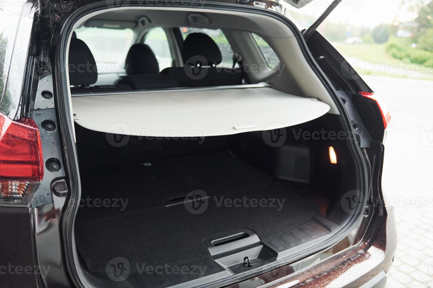 Rear particle view of modern black automobile with car trunk open photo