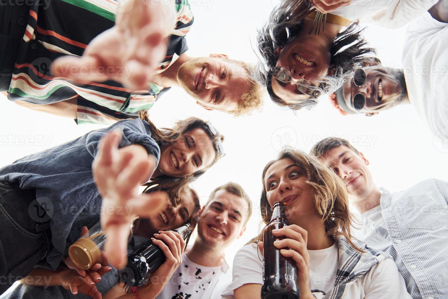 mirando abajo. vista desde abajo. un grupo de jóvenes con ropa informal tienen una fiesta en la azotea juntos durante el día foto
