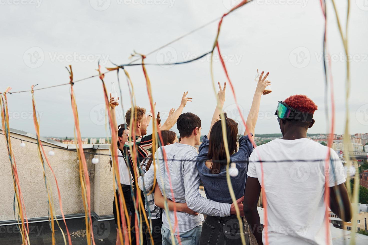 Decorated place. Cloudy weather. Group of young people in casual clothes have a party at rooftop together at daytime photo