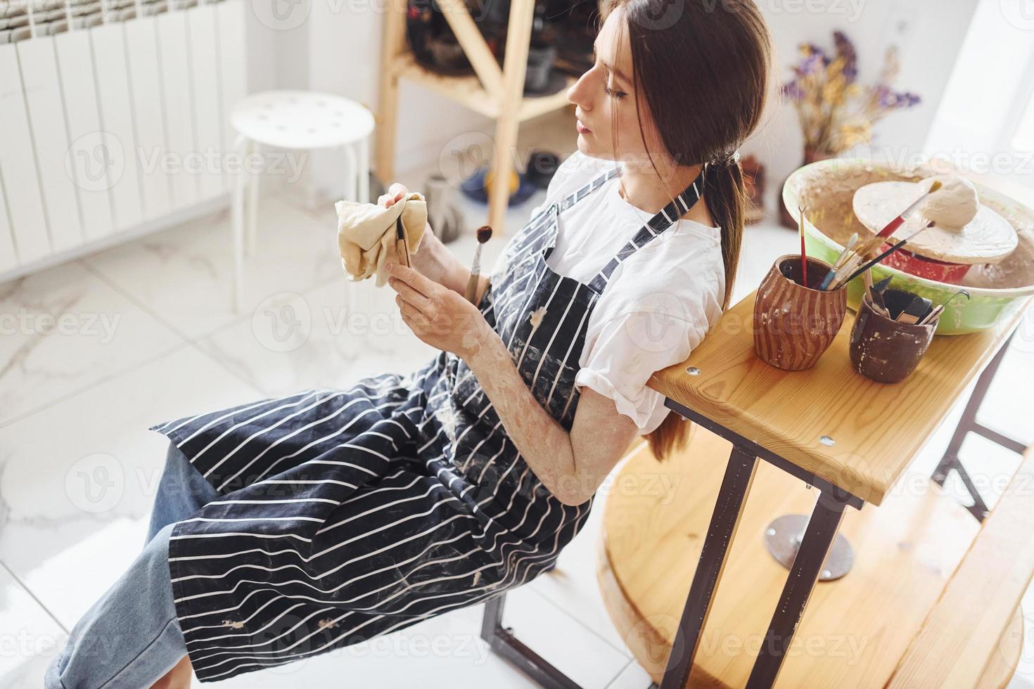 Young female ceramist indoors with handmade clay product. Conception of pottery photo