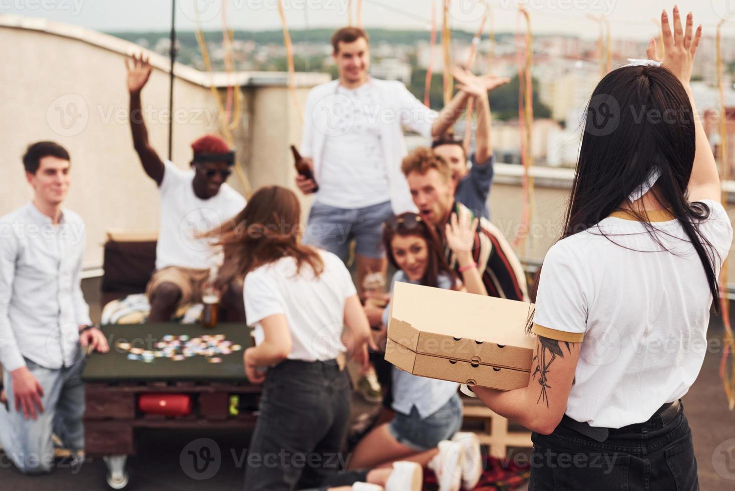 Delicious pizza. Group of young people in casual clothes have a party at rooftop together at daytime photo