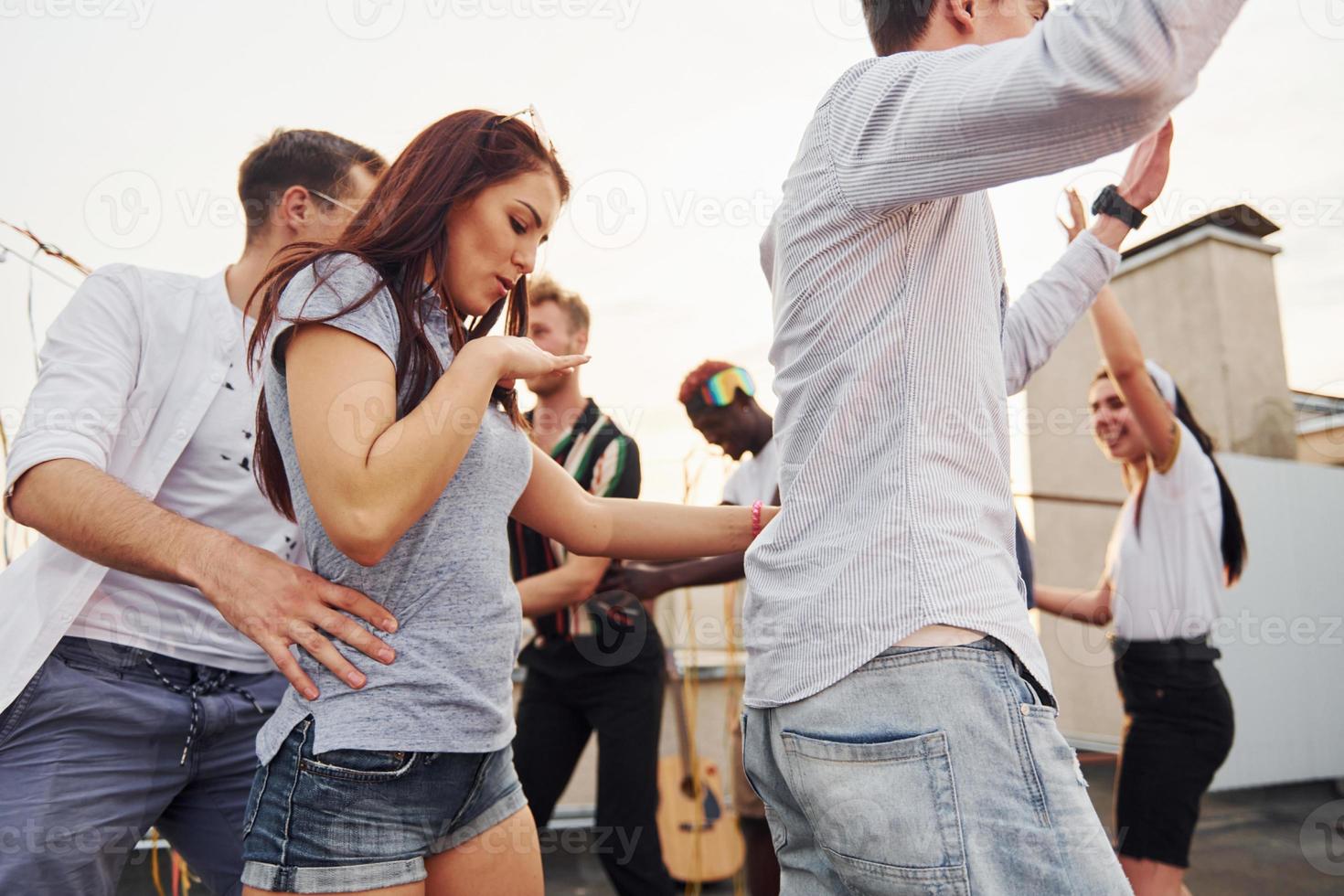 Recreation time. Group of young people in casual clothes have a party at rooftop together at daytime photo