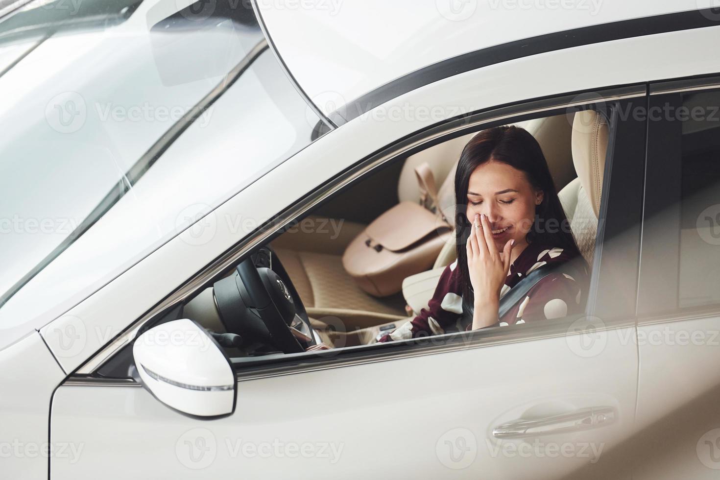 vista lateral de la hermosa joven morena que está dentro del automóvil moderno. montar coche foto