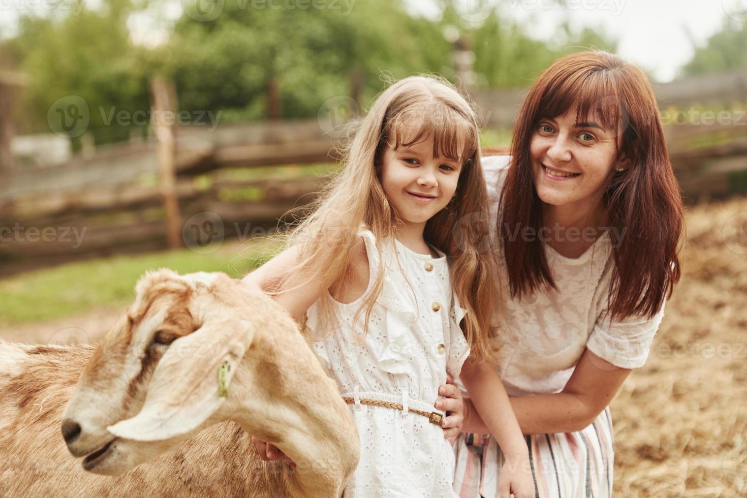 Young mother with her daughter is on the farm at summertime photo