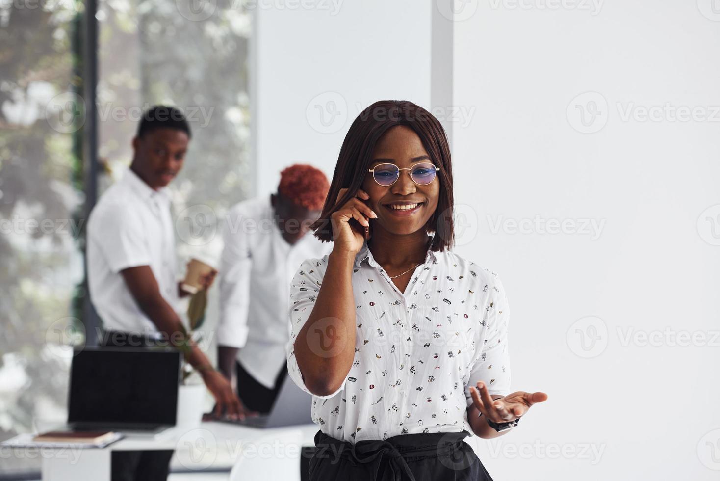 Portrait of woman in glasses. Group of african american business people working in office together photo