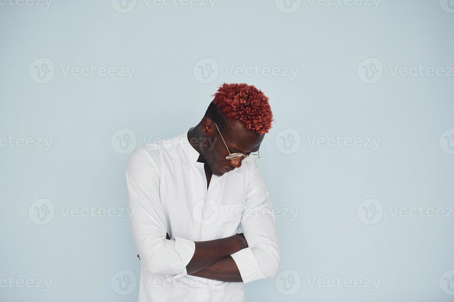 Young african american man in white formal clothes standing against wall indoors photo