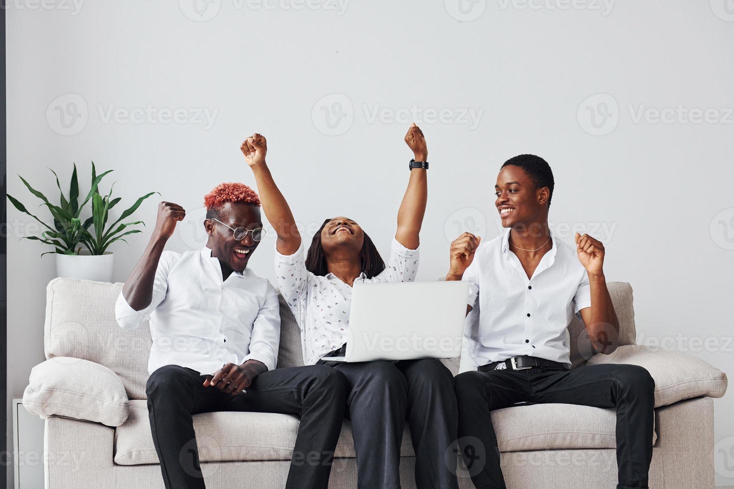 cómodo sofá. usando una computadora portátil grupo de empresarios afroamericanos que trabajan sentados juntos foto