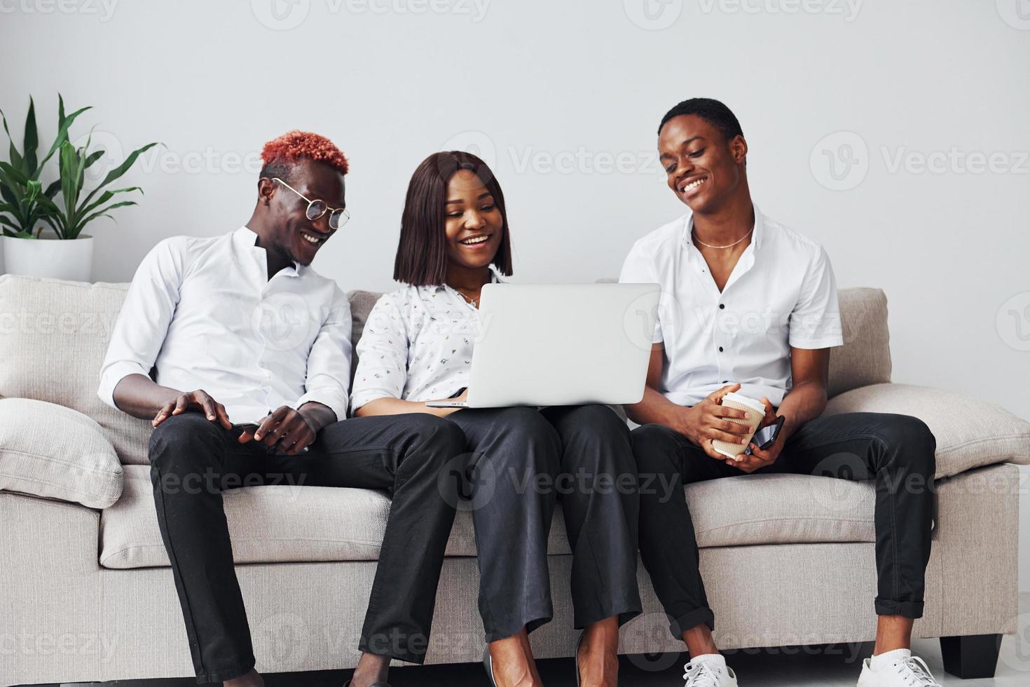 Comfortable sofa. Using laptop. Group of african american business people working when sitting together photo