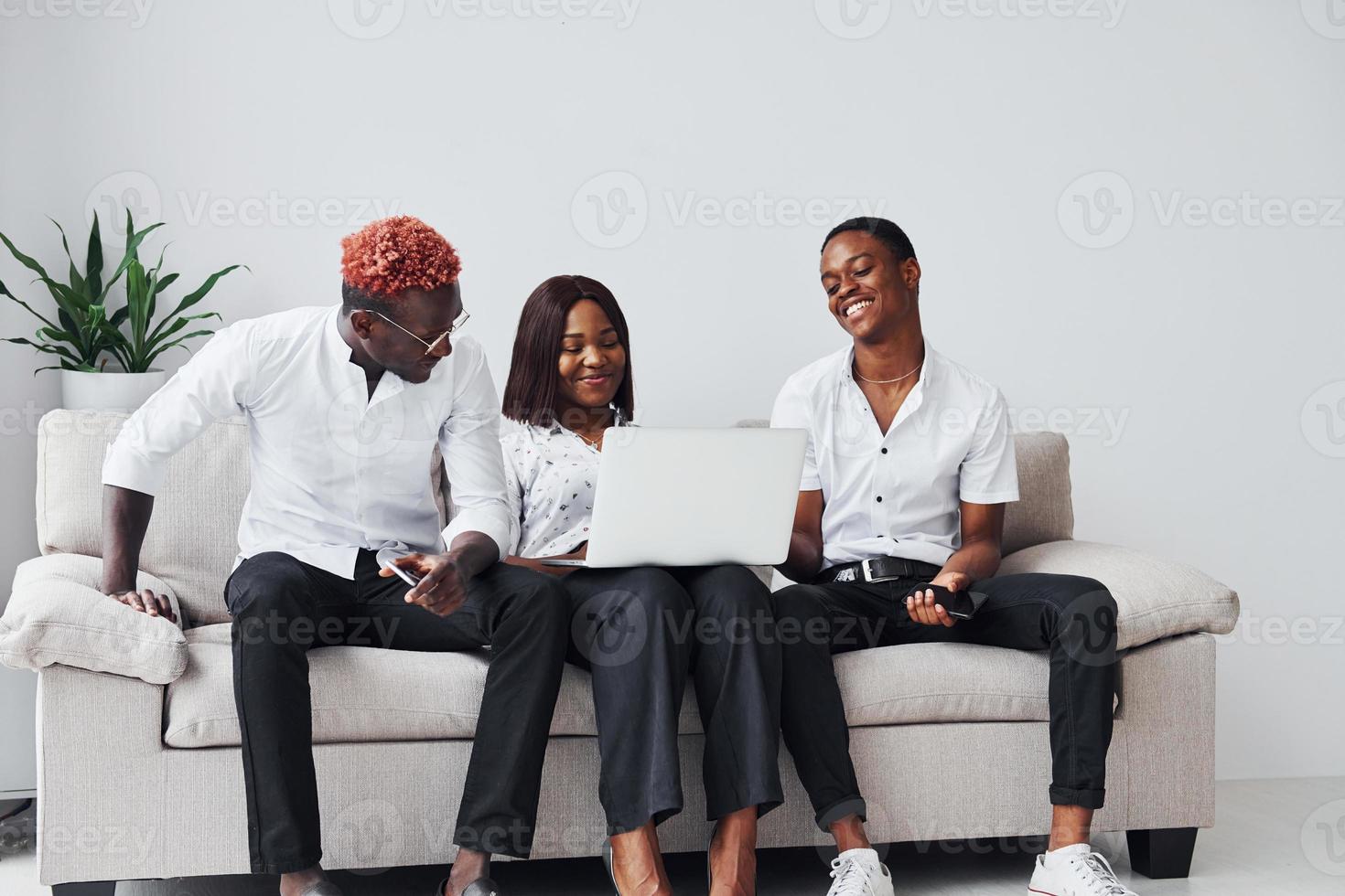 Comfortable sofa. Using laptop. Group of african american business people working when sitting together photo