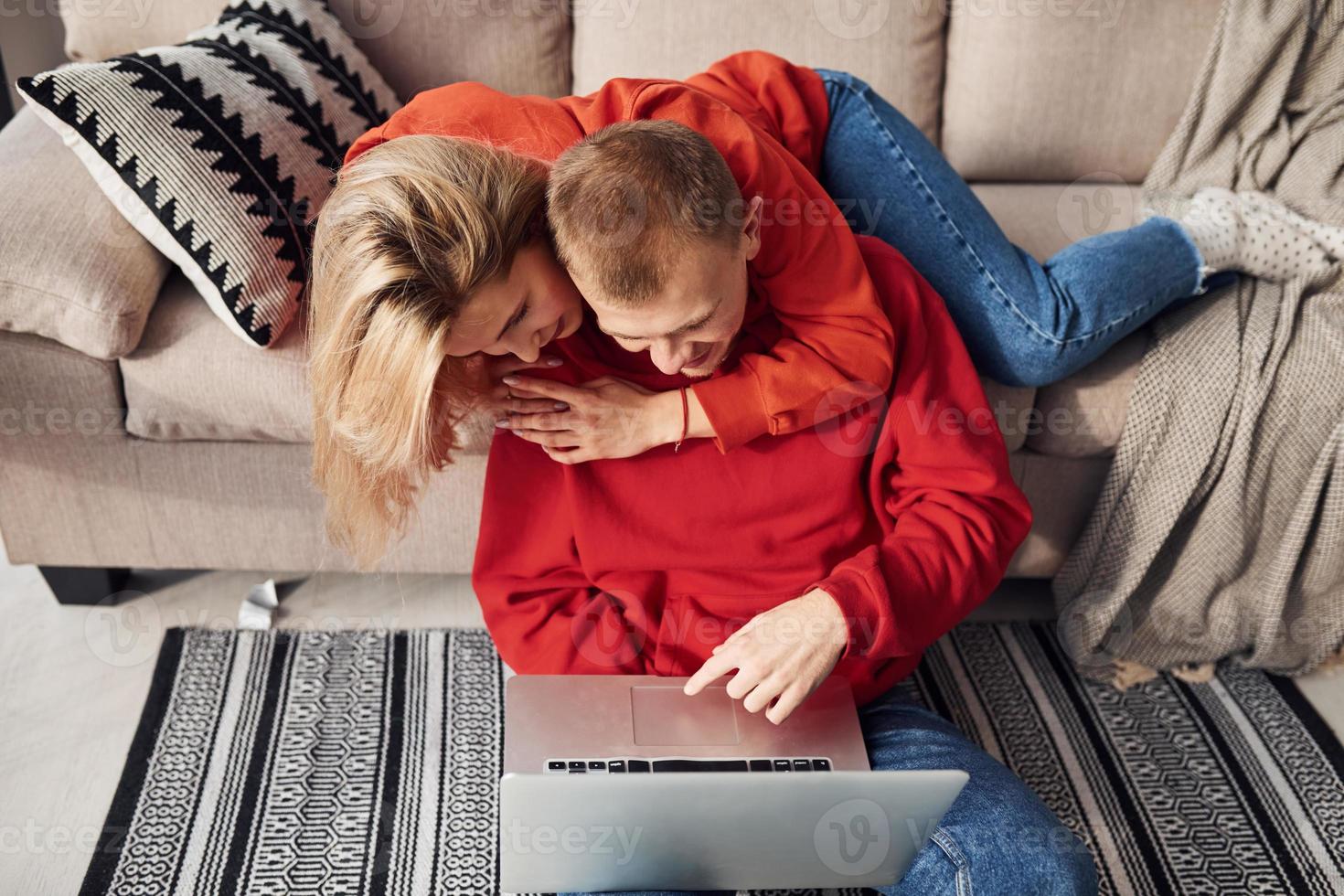 Using laptop that is on the legs. Young lovely couple together at home spending weekend and holidays together photo