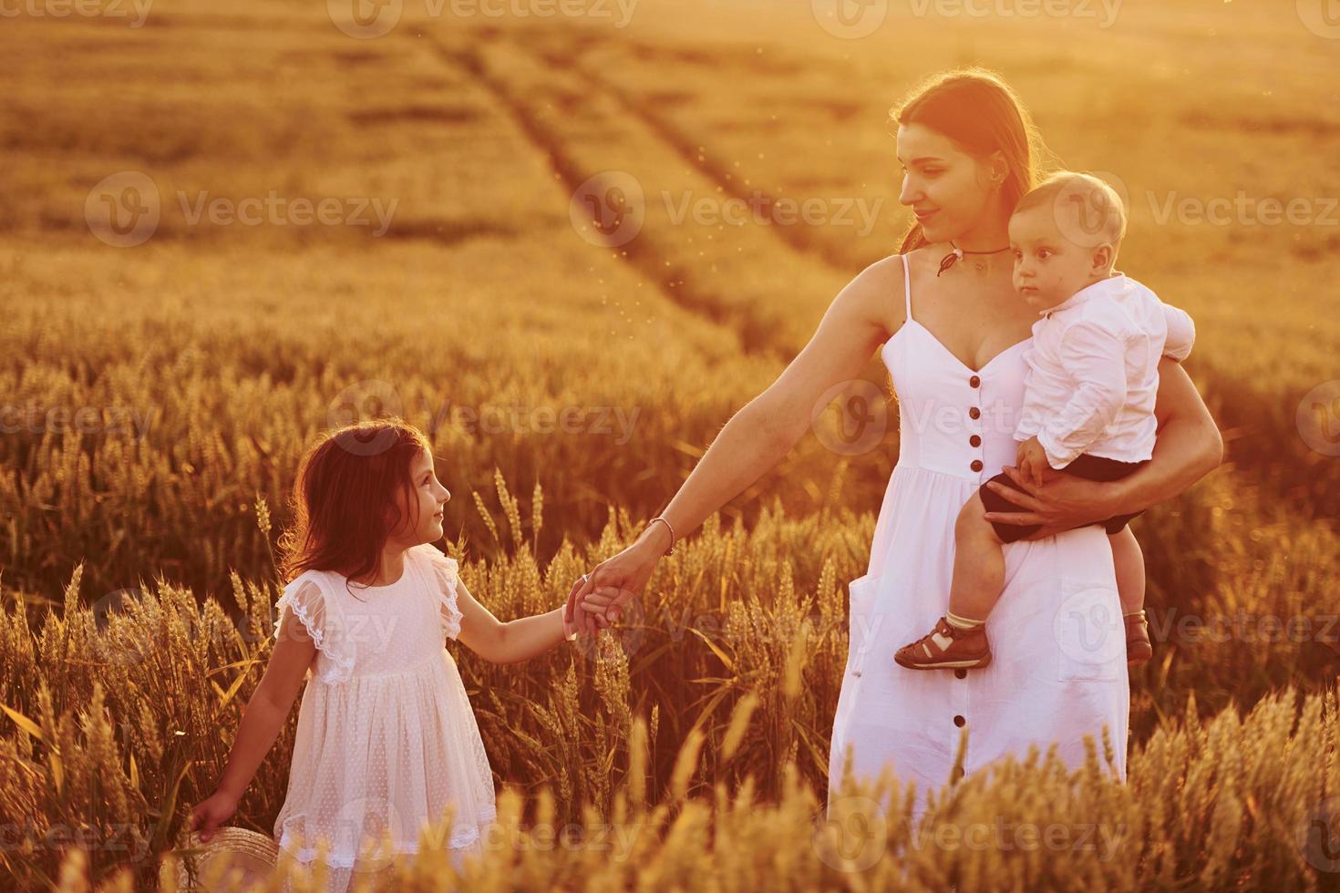 alegre familia de madre, hijo pequeño e hija que pasan tiempo libre en el campo en el día soleado del verano foto