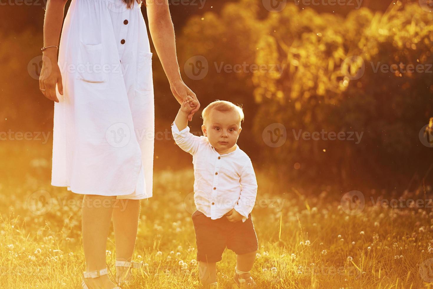 Mother standing with her son at free time on the field at sunny day time of summer photo