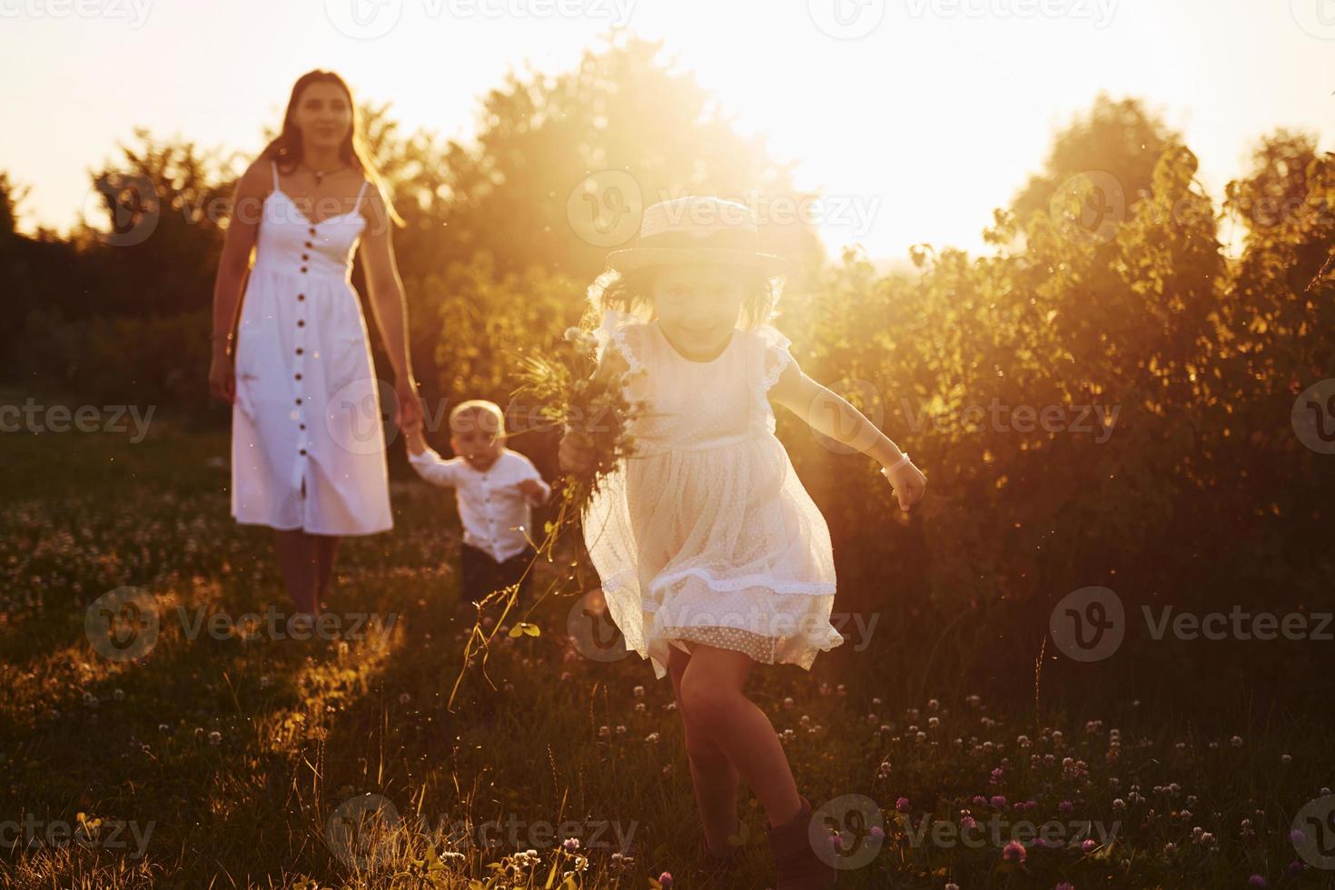 hermoso rayo de luz. madre con niño y niña pasando tiempo libre en el campo en un día soleado de verano foto