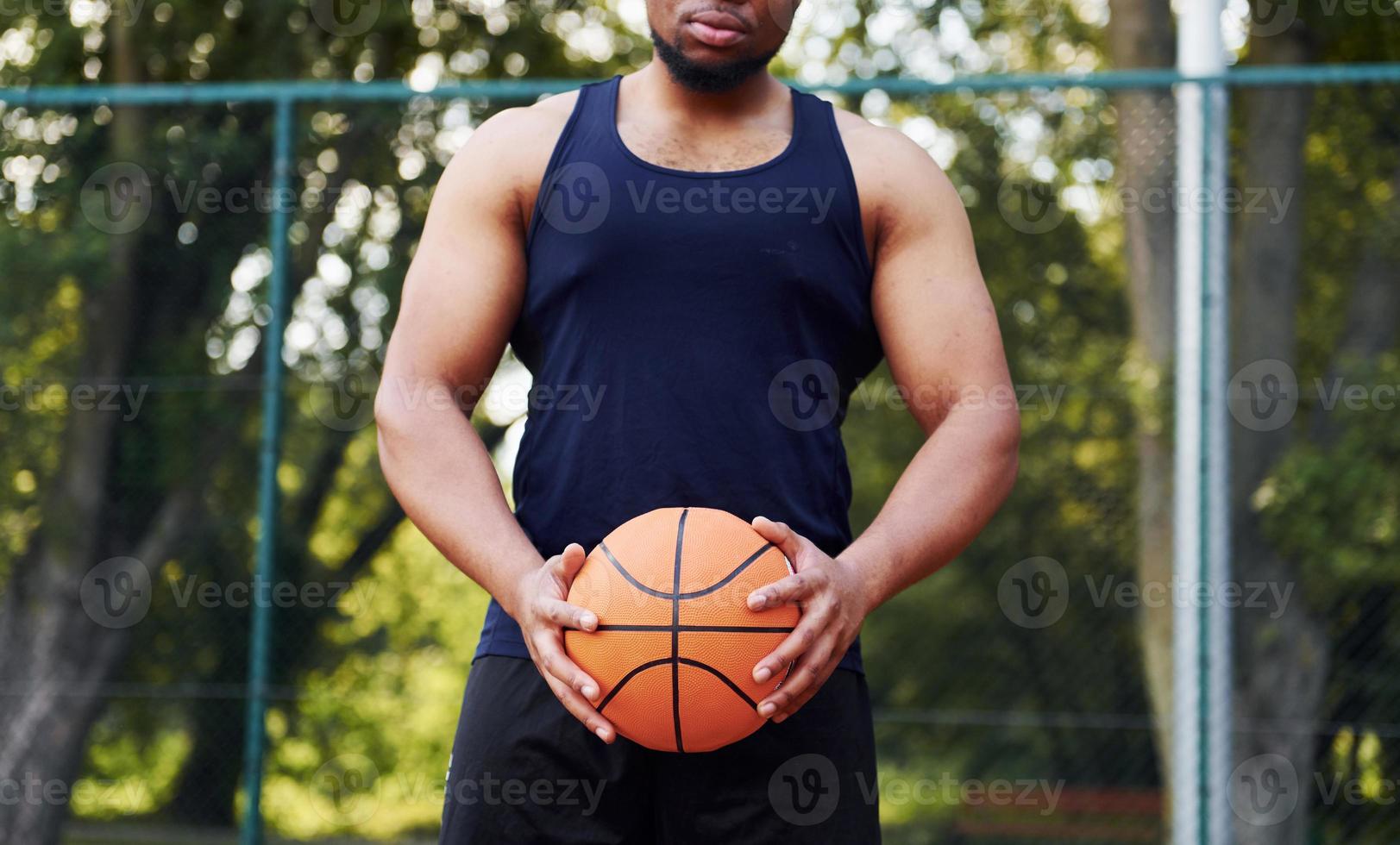 African american man standing with ball on the court outdoors photo