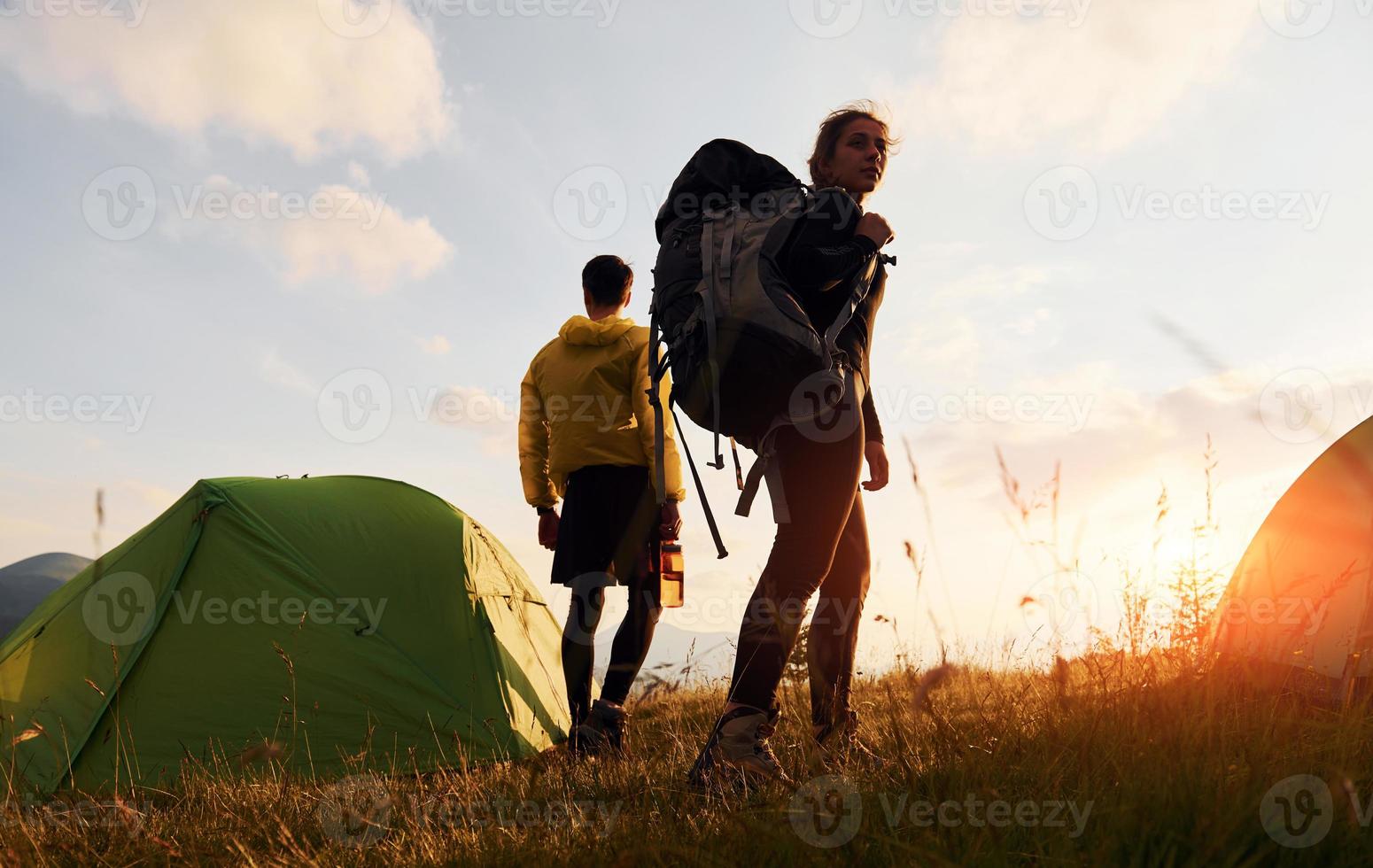 Couple having a walk outdoors near green tent. Conception of traveling photo