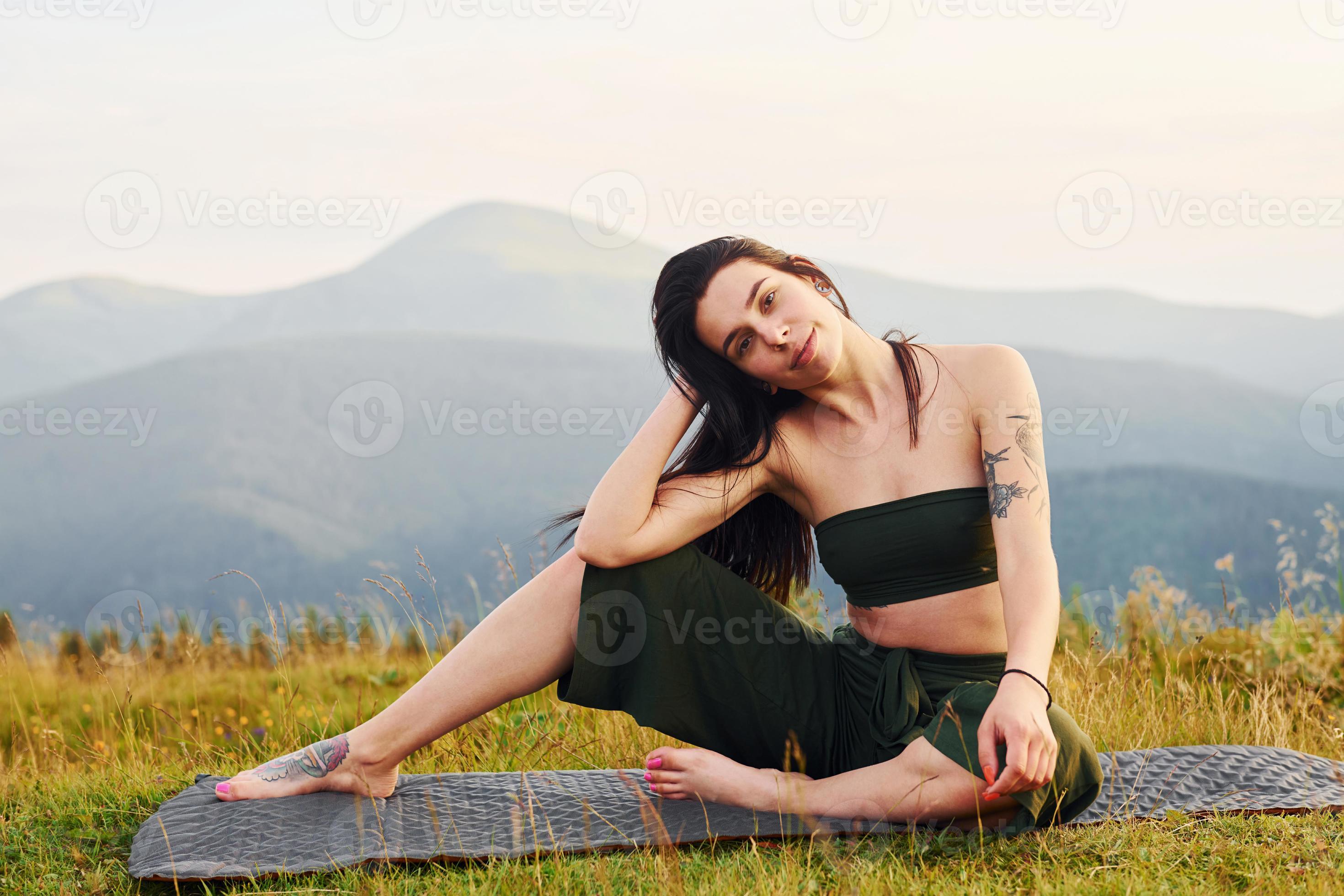 Cute brunette sits on yoga mat. Majestic Carpathian Mountains. Beautiful  landscape of untouched nature 15298395 Stock Photo at Vecteezy