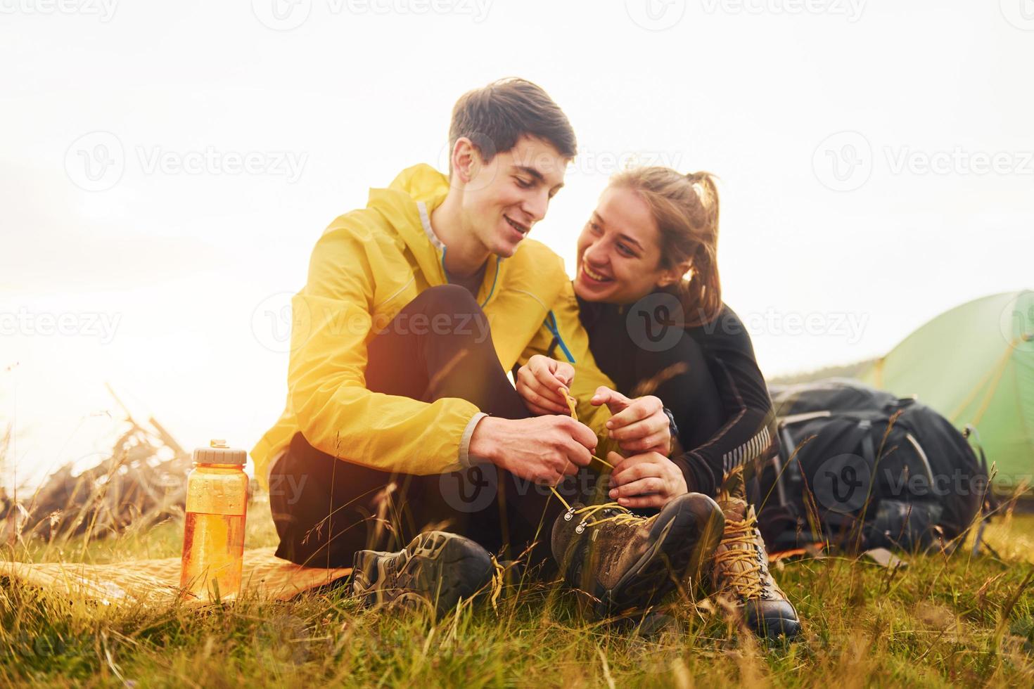 Young lovely couple sitting near tent outdoors at daytime. Beautiful sunlight photo