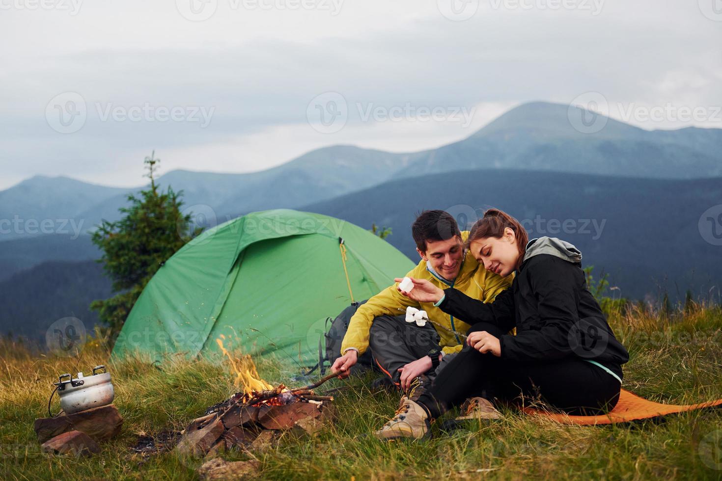 Couple with marshmallow near campfire. Majestic Carpathian Mountains. Beautiful landscape of untouched nature photo