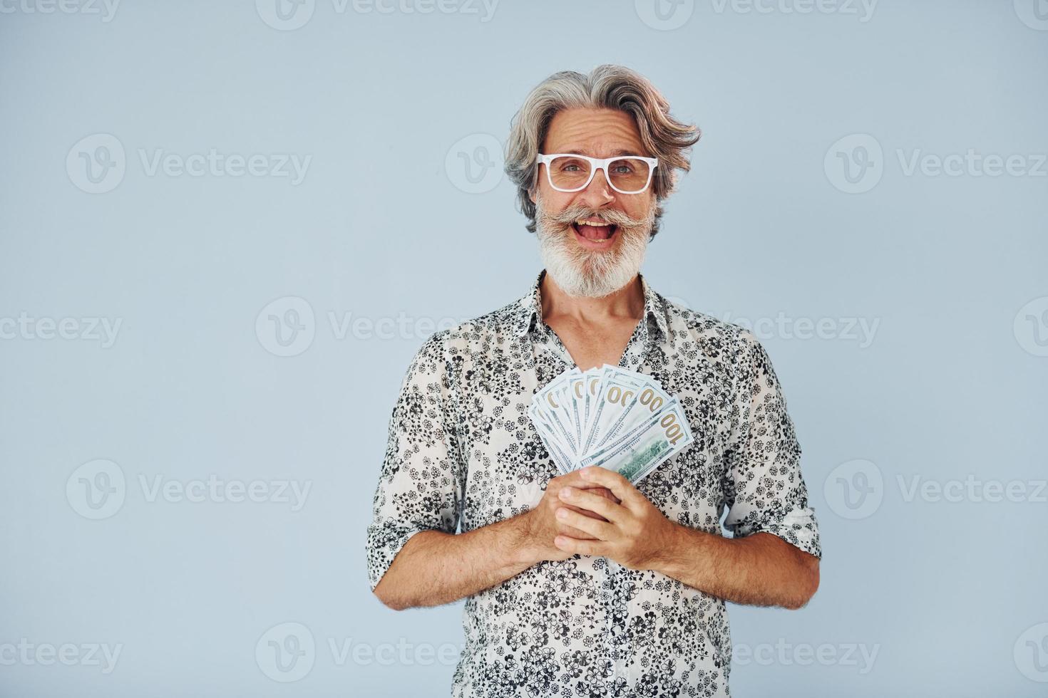 Millionaire with cash in hands. Senior stylish modern man with grey hair and beard indoors photo