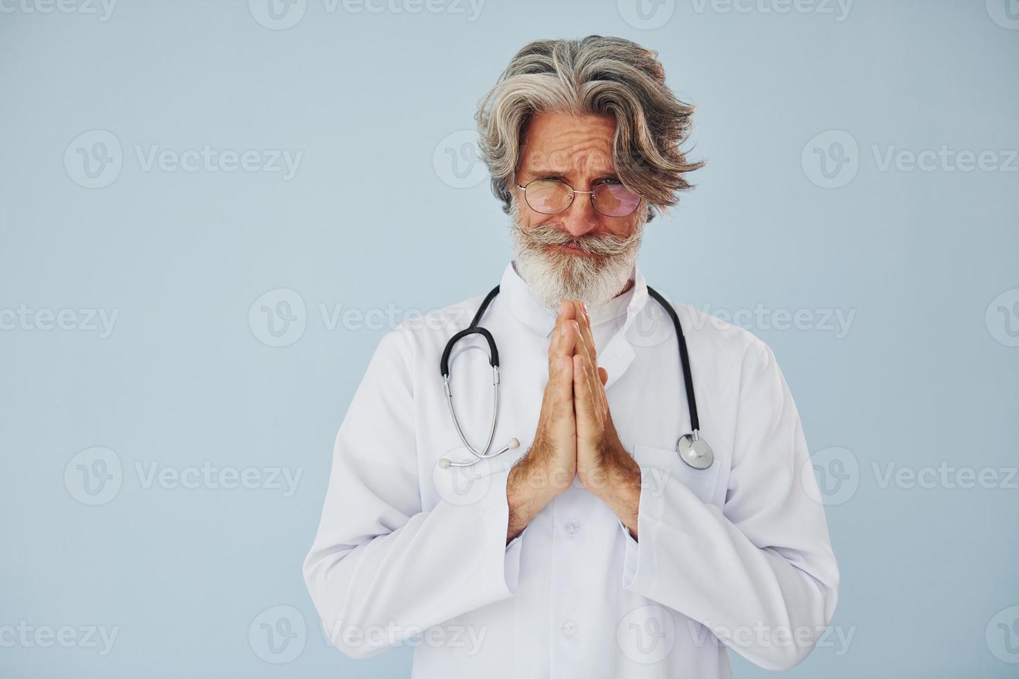 médico positivo profesional. Senior hombre moderno con estilo con pelo gris y barba en el interior foto