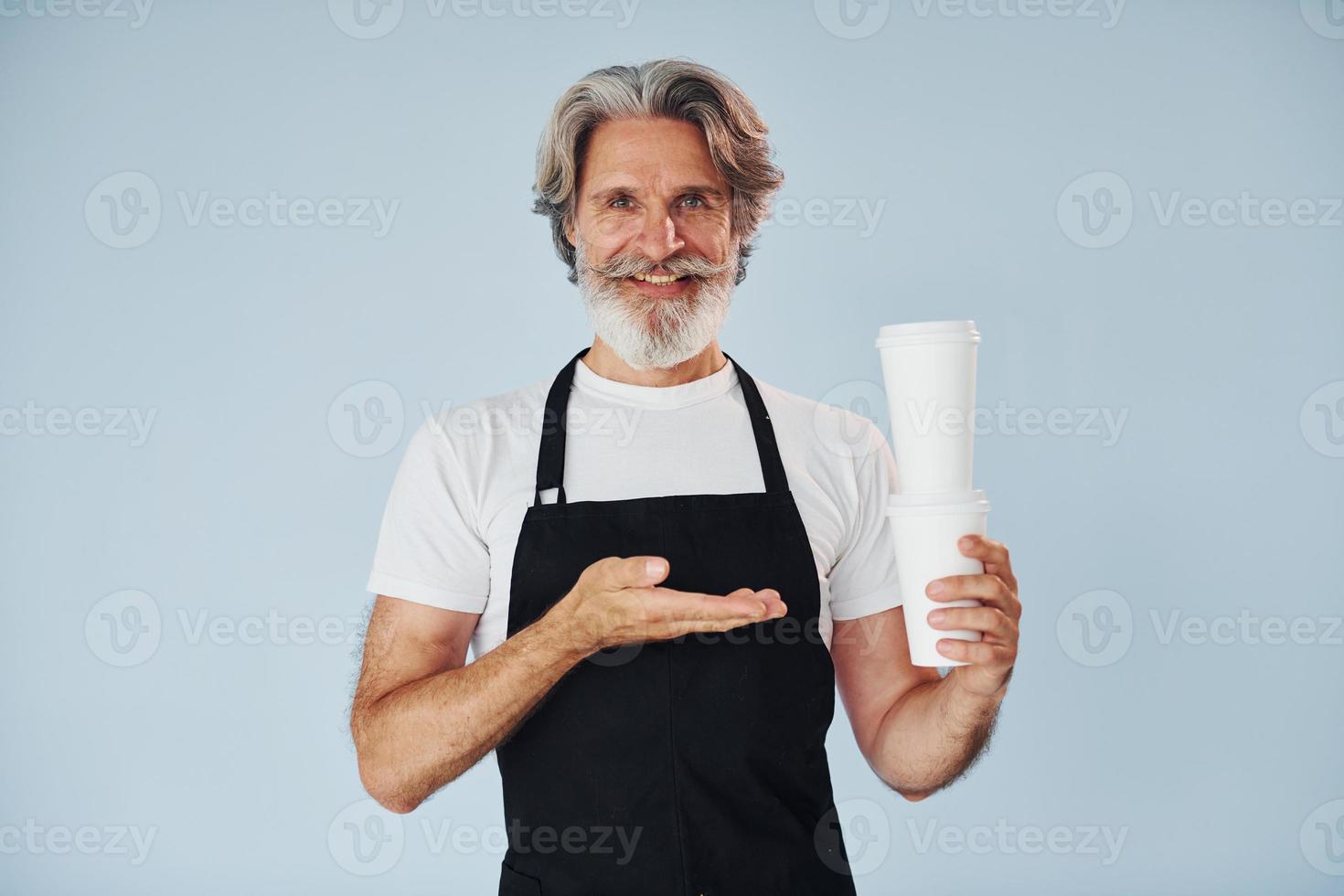 Waiter with drinks in hands. Senior stylish modern man with grey hair and beard indoors photo
