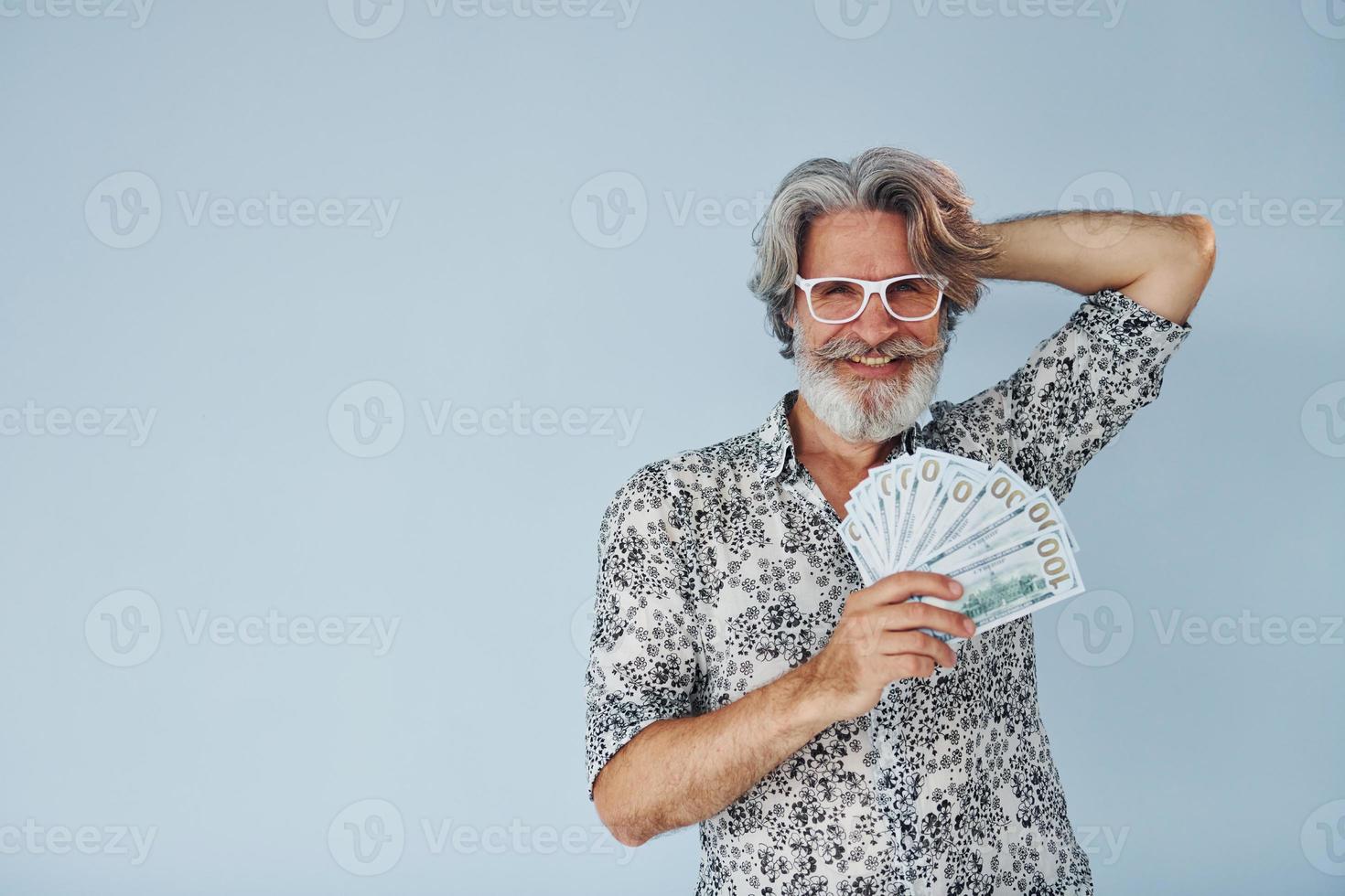 Millionaire with cash in hands. Senior stylish modern man with grey hair and beard indoors photo