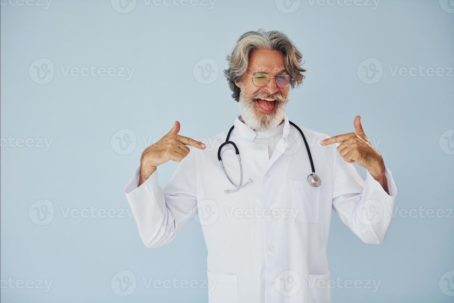 médico positivo profesional. Senior hombre moderno con estilo con pelo gris y barba en el interior foto