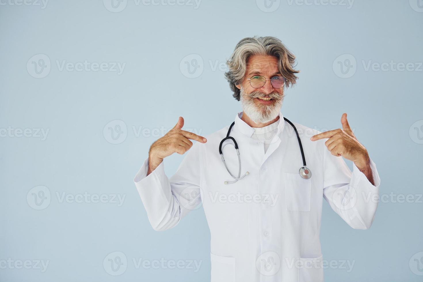 Professional positive doctor. Senior stylish modern man with grey hair and beard indoors photo