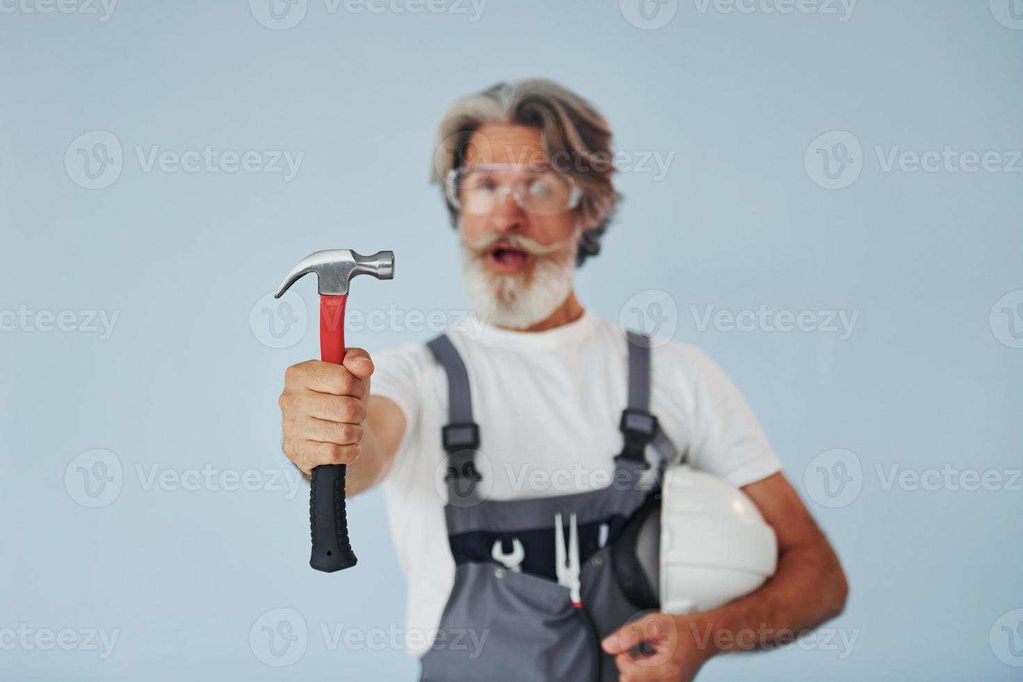 reparador listo para trabajar. Senior hombre moderno con estilo con pelo gris y barba en el interior foto