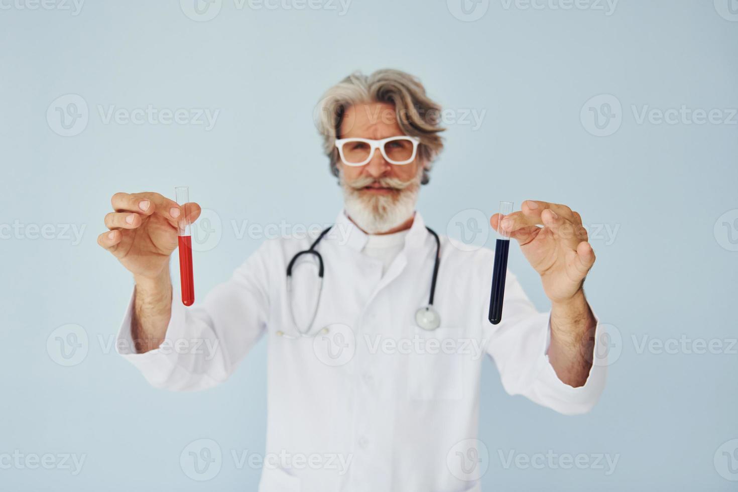 Doctor holds test tubes. Senior stylish modern man with grey hair and beard indoors photo